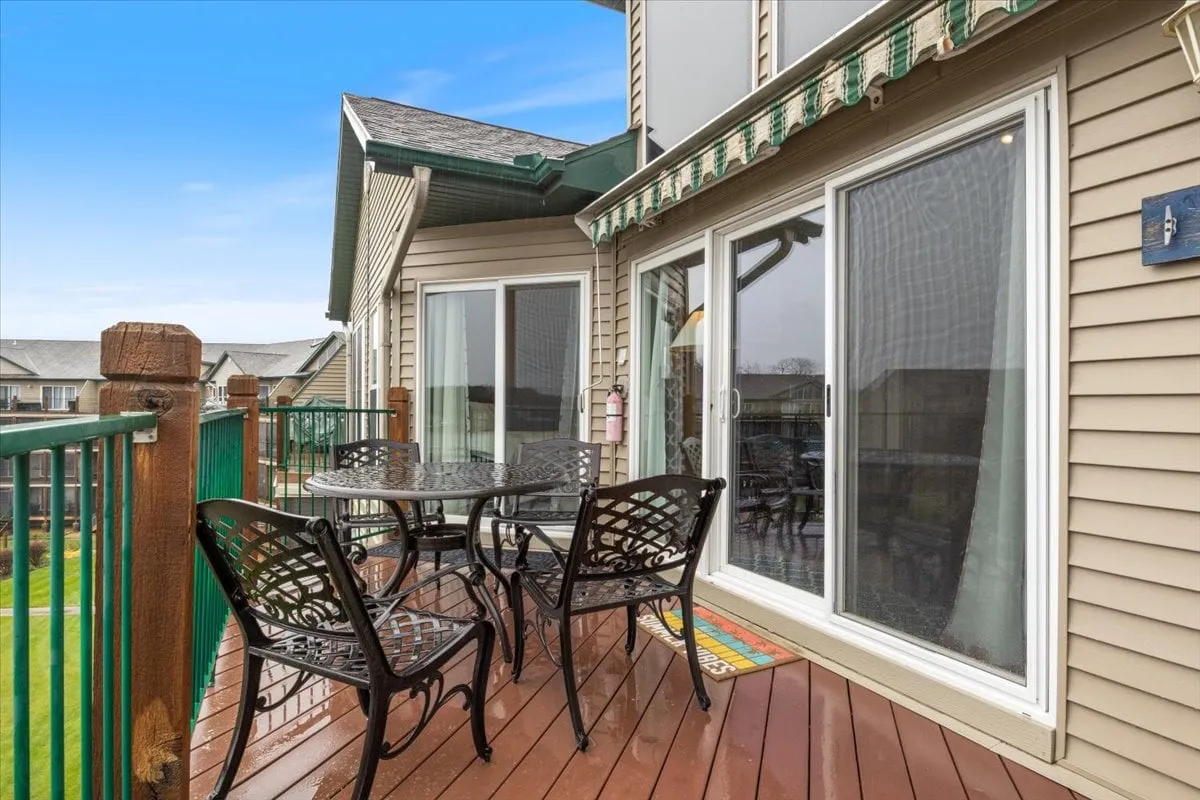 An inviting view of a deck with a table and chairs set, glass doors leading inside, and protective awnings above. The orientation suggests easy indoor-outdoor flow, ideal for gathering, grilling, and evening relaxation.