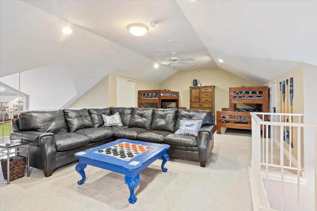 This image presents a large sectional sofa paired with a colorful coffee table and visible bunk beds in the background. The space is inviting and multifunctional—ideal for family gatherings, game nights, relaxing, or providing extra sleeping space in an open, communal area.