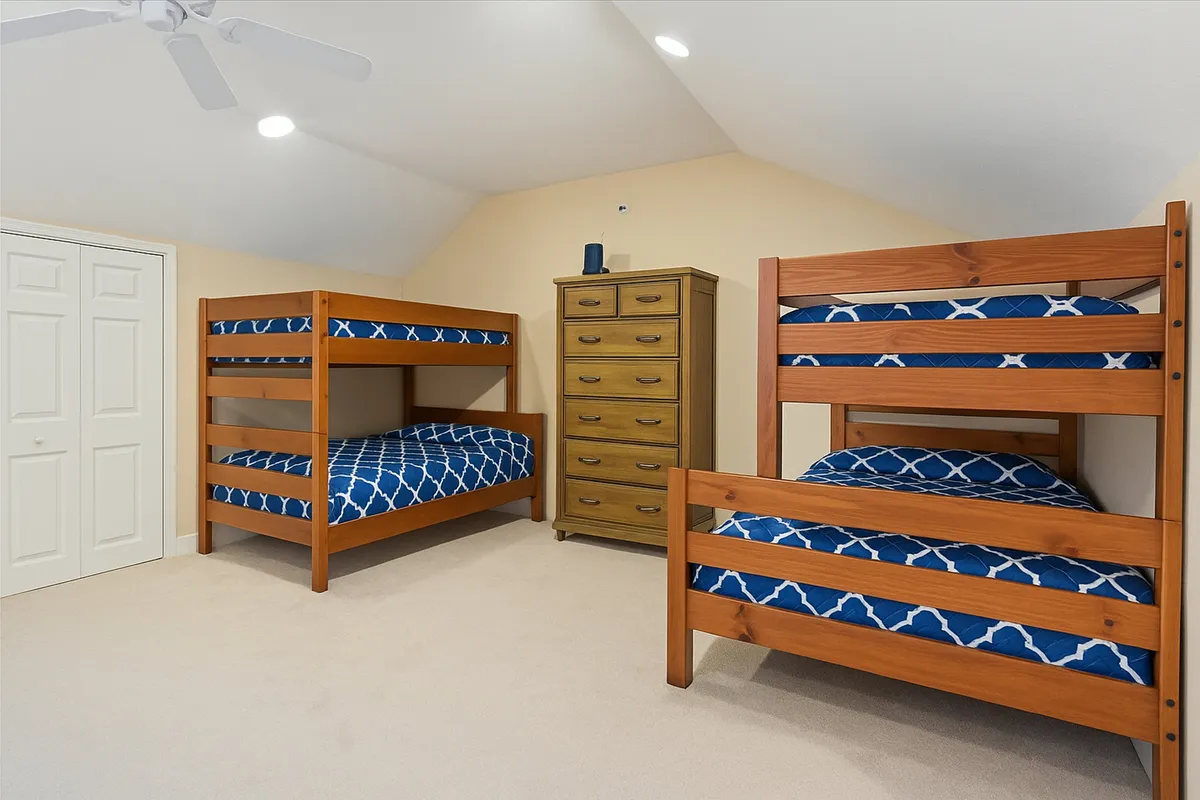 This image depicts a set of cozy bunk beds next to a dresser, creating a warm and family-friendly environment. The setup is ideal for children or groups, emphasizing shared experiences and late-night chats.